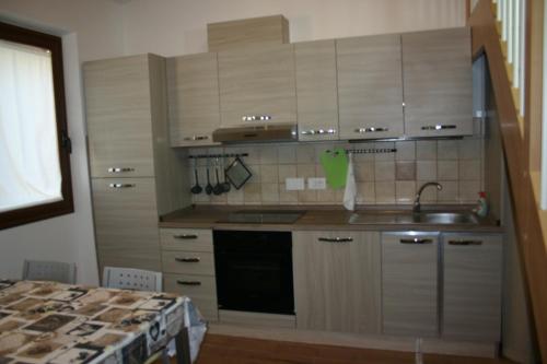 a kitchen with wooden cabinets and a sink and a stove at A casa di Giò in Loreto