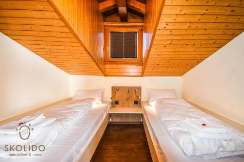 two beds in a small room with wooden ceilings at Haus Camillo in Saas-Fee