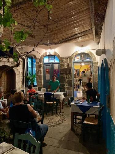 a group of people sitting at tables in a restaurant at Traumhaus Nisyros in Páloi
