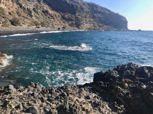 a person in the water near a rocky beach at Traumhaus Nisyros in Páloi