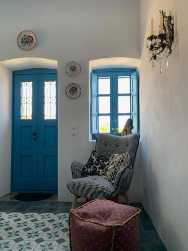 a living room with a chair and blue doors at Traumhaus Nisyros in Páloi