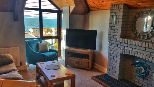 a living room with a tv and a fireplace at The Rocks in Westward Ho