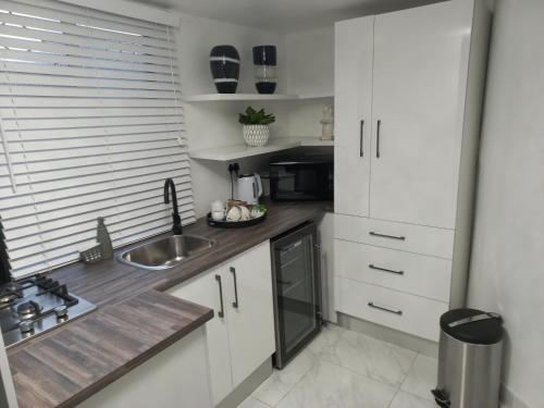 a kitchen with white cabinets and a sink at North Haven Country Estate in Honeydew