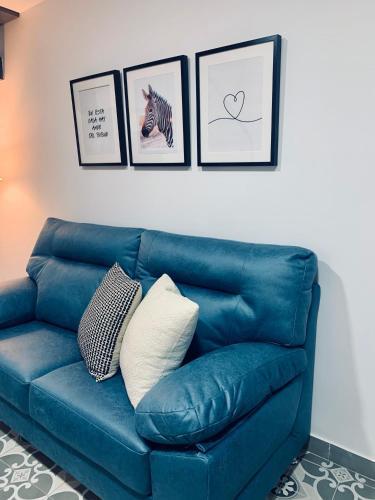 eine blaue Couch in einem Wohnzimmer mit Bildern an der Wand in der Unterkunft Bodegas de Felicidad in Setenil de las Bodegas