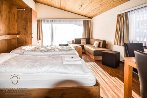 a hotel room with two beds and a couch at Haus Camillo in Saas-Fee