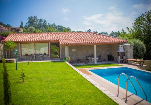a backyard with a swimming pool and a house at DreamVille- Casa da Pedral in Arcos de Valdevez