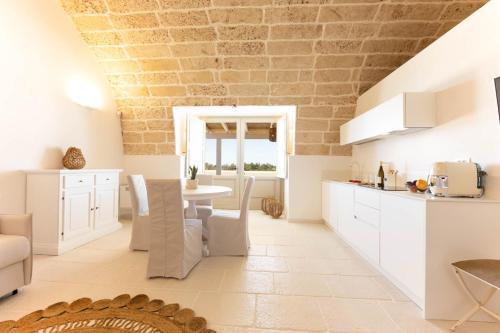 a kitchen and dining room with white cabinets and a table at Masseria Macchiaforte in Gallipoli