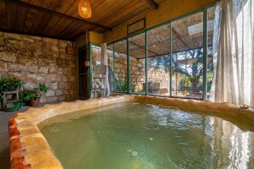 una gran piscina en una casa con una gran ventana en Hemdatya Stone Suites In The Galilee, en Ilaniyya