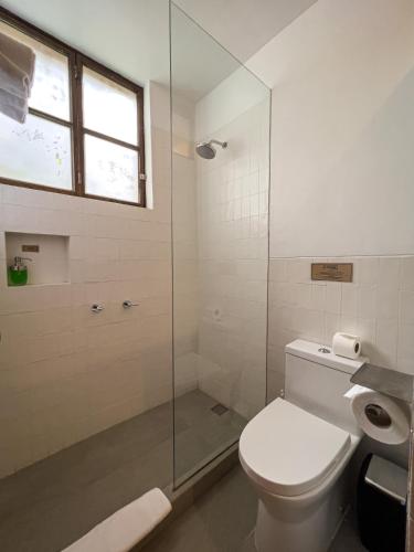 a bathroom with a toilet and a glass shower at El Albergue Ollantaytambo in Ollantaytambo