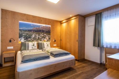 1 dormitorio con 1 cama con una foto en la pared en Apartments Picenin, en La Villa