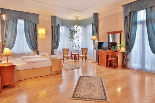 een slaapkamer met een bed en een tafel en stoelen bij Belvedere Wellness Hotel in Mariánské Lázně