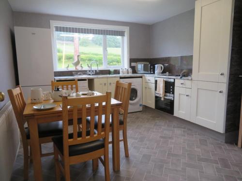 a kitchen with a table and chairs and a kitchen with a microwave at Marr Cottage in Thornhill