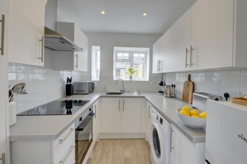 a white kitchen with a sink and a dishwasher at Brewery Loft - 3 Bedroom Bright Spacious apartment in the centre of town, Wifi, Netflix in Cirencester