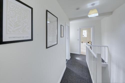 a hallway with white walls and pictures on the wall at Brewery Loft - 3 Bedroom Bright Spacious apartment in the centre of town, Wifi, Netflix in Cirencester