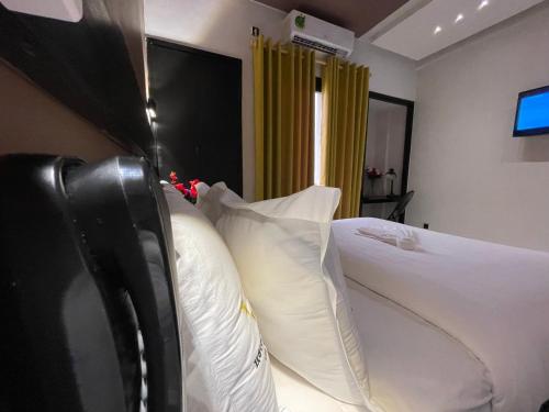 a bedroom with a bed with white pillows at Hôtel Vendôme Douala in Douala