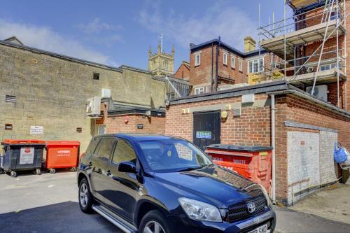 a small blue car parked in front of a brick building at Brewery Loft - 3 Bedroom Bright Spacious apartment in the centre of town, Wifi, Netflix in Cirencester
