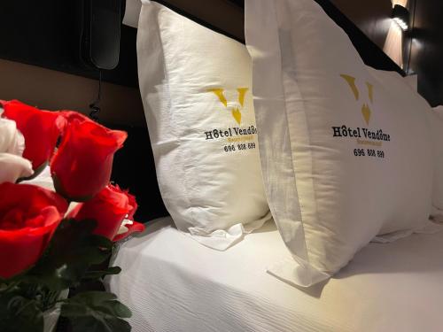 a bed with white pillows and red roses on it at Hôtel Vendôme Douala in Douala