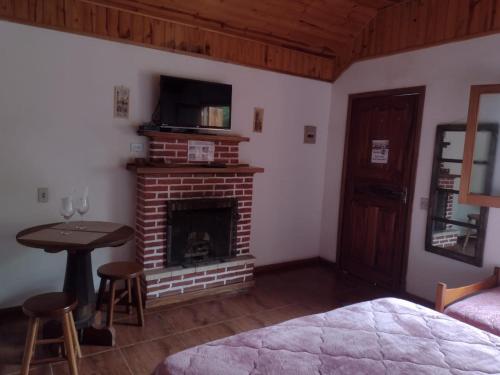 um quarto com uma lareira, uma cama e uma mesa em Pousada Chales Monte Verde em Monte Verde