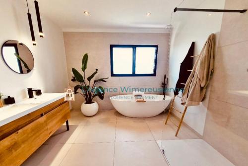 a bathroom with a large tub and a sink at Magnifique villa avec jaccuzi in Wimille