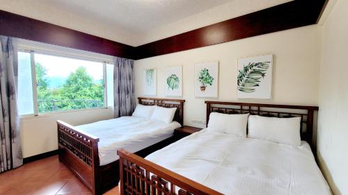 2 Betten in einem Zimmer mit Fenster in der Unterkunft 杉羽松民宿 Seeing A Song INN in Luodong