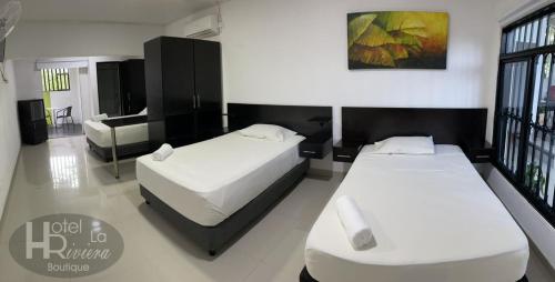 a hotel room with two beds and a couch at Hotel Boutique La Riviera in Rivera