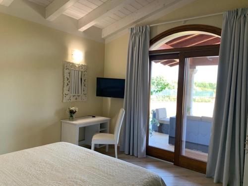 ein Schlafzimmer mit Bett, Schreibtisch und Fenster in der Unterkunft Corte dei Mirti, Appartamento indipendente con ampia veranda in Iglesias