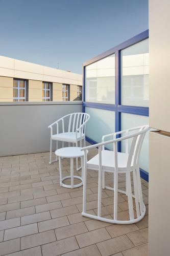 two white chairs and a refrigerator on a balcony at Iraipe Logroño Hotel in Logroño