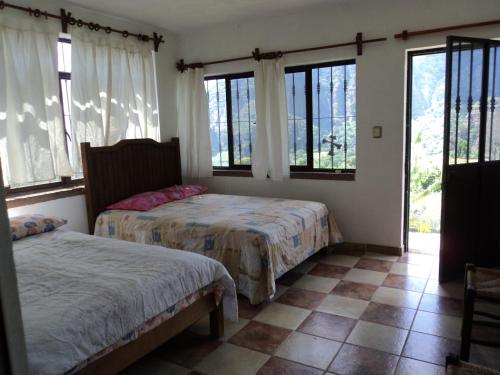 2 Betten in einem Zimmer mit Fenstern und Fliesenböden in der Unterkunft Posada Xamicalli in Tlayacapan