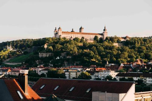 a castle on top of a hill with houses at DAS v EVERT Hotel - am Congress Centrum Würzburg in Würzburg