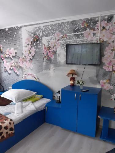 a bedroom with a blue bed and a wall with flowers at Vila Muntii Bucegi & SPA in Bran