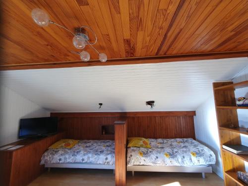 Schlafzimmer mit einem Bett mit Holzdecke in der Unterkunft Chez Gilles et Eveline in Cruet