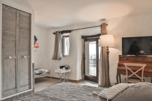 a bedroom with a bed and a television and a piano at Maison d'hôtes Le Hameau de la Mûre in Saint-Laurent-du-Pape