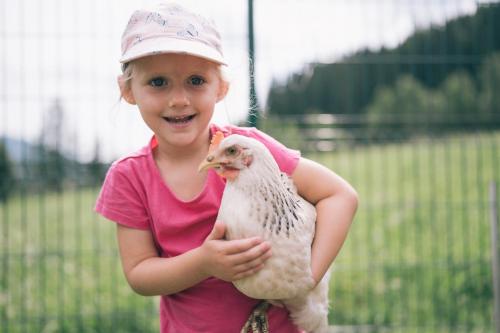 a little girl holding a chicken in her hands at Der Kirchheimerhof - Superior in Bad Kleinkirchheim