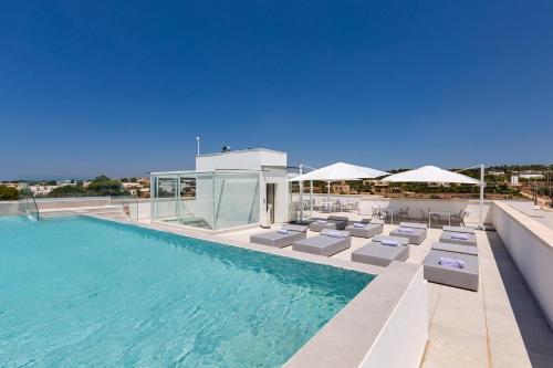 a pool with chairs and umbrellas on a building at Perla Saracena Hotel & Restaurant in Salve