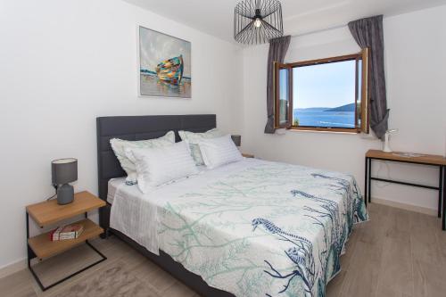 ein Schlafzimmer mit einem Bett mit Blick auf das Meer in der Unterkunft Villa Maestral in Vinišće