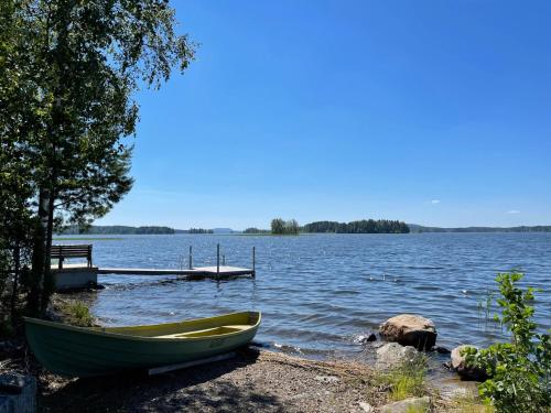a green boat sitting on the shore of a lake at Säilöksen Lomahuvilat in Luhanka