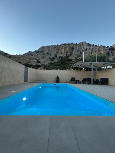 a blue swimming pool with a mountain in the background at Tesoro Del Mare in Pefki