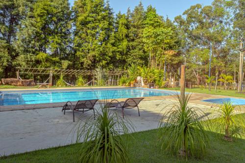 a swimming pool with two chairs in a yard at Pousada DuBaldo in Holambra