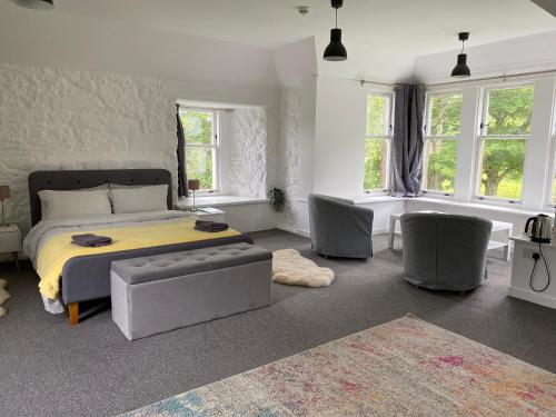 a bedroom with a bed and some chairs and windows at Hartfield House Hostel in Applecross
