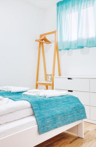 a white room with a bed with a blue blanket at 365Balaton Apartmanok in Alsóörs