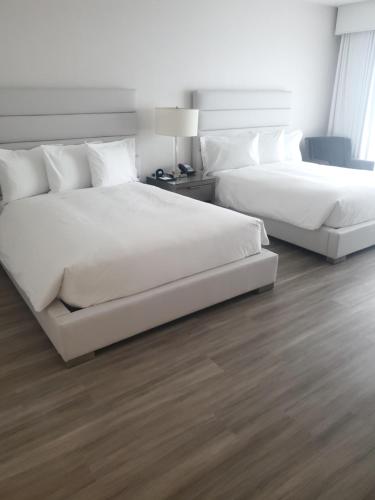 two beds in a hotel room with white sheets at Grand Hotel in Sunnyvale