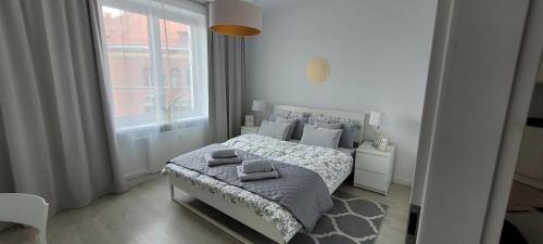 biała sypialnia z łóżkiem i oknem w obiekcie Apartament Centrum Szczecin w Szczecinie