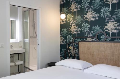 a bedroom with a bed and a bathroom with a wallpaper at Hotel De Suez in Paris