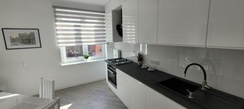 cocina con armarios blancos y encimera negra en Apartament Centrum Szczecin en Szczecin