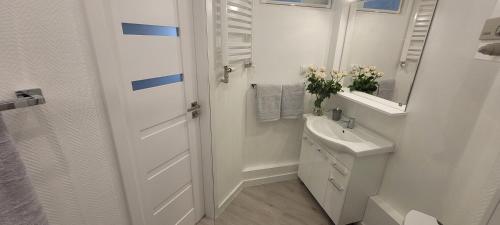 W białej łazience znajduje się umywalka i lustro. w obiekcie Apartament Centrum Szczecin w Szczecinie