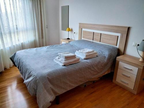 ein Schlafzimmer mit einem Bett mit drei Handtüchern darauf in der Unterkunft Piso con piscina en Sada in Sada