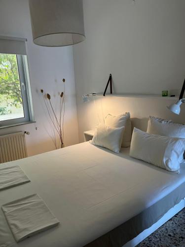 a large white bed with white pillows and a window at Cloudberry in Kalyves