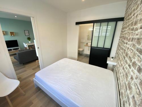 1 dormitorio con 1 cama blanca y sala de estar en Le Rémois - PARKING - Cour privative - WIFI, en Reims