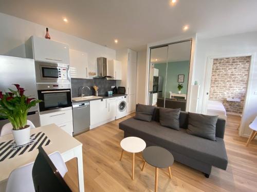 sala de estar con sofá y cocina en Le Rémois - PARKING - Cour privative - WIFI, en Reims