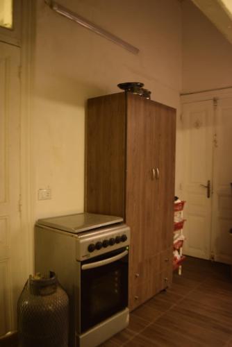 a kitchen with a stove and a wooden cabinet at City Hostel Dormitory in Trâblous